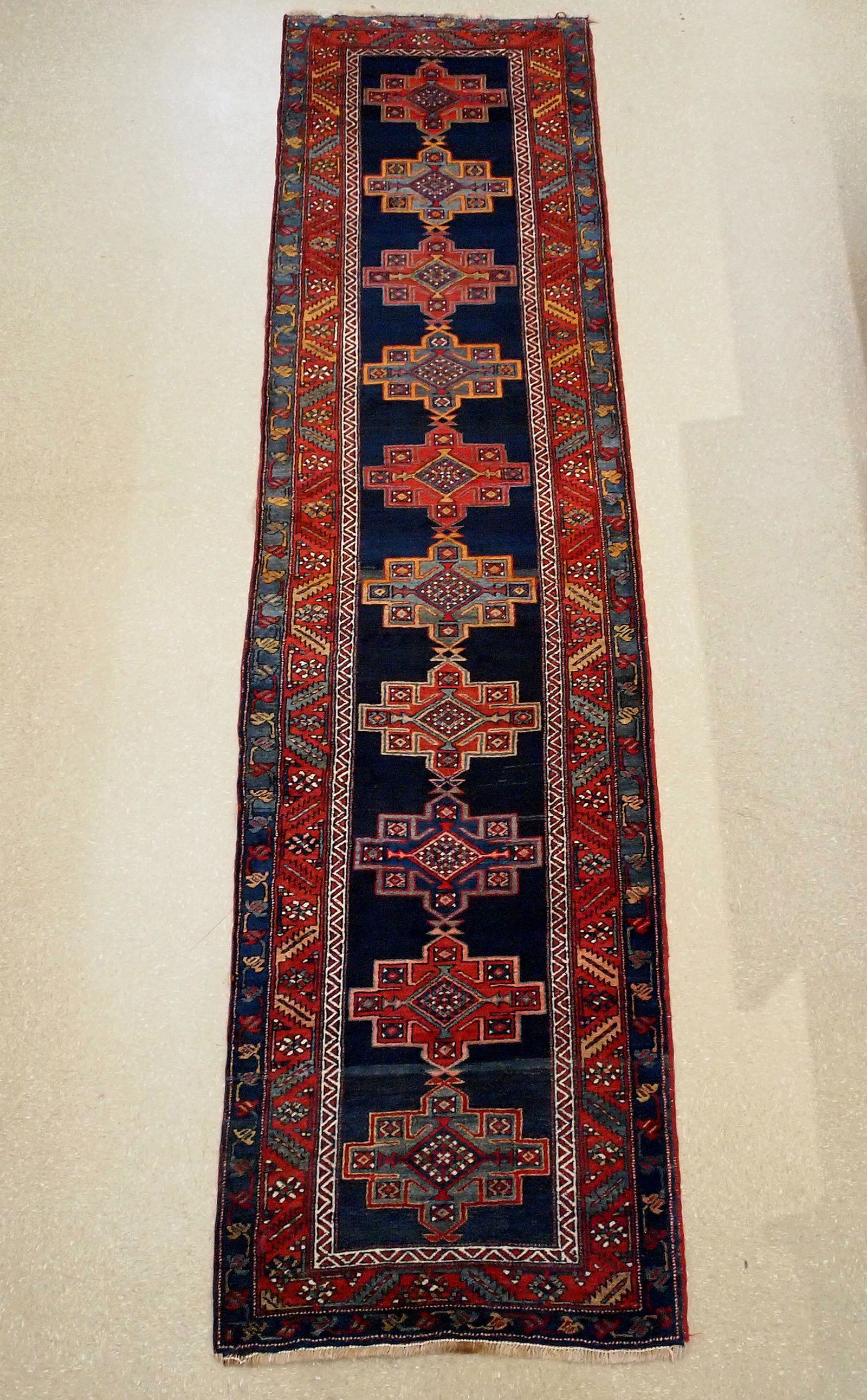 Persian Hamadan Runner: An older 3.3 x 13.2' Persian Hamadan runner. Multiple geometric medallions on a Navy Blue field within a multi-color border. Some wear, edge damage. ESTIMATE $400-600