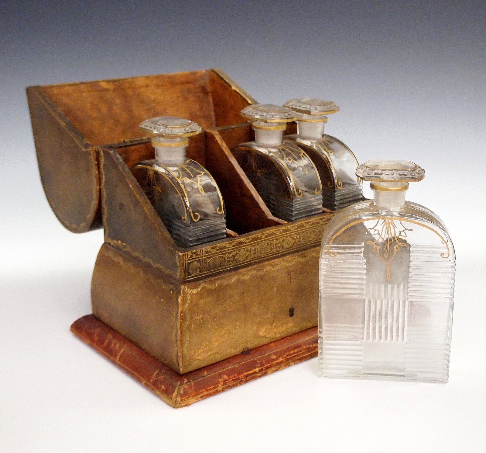 Italian Tantalus: A turn of the century Italian tantalus. A wooden dome top box with tooled leather covering contains four molded decanters with gilded detail. Wear and scratches to the leather. 9 1/4 x 6 x 9" high. ES