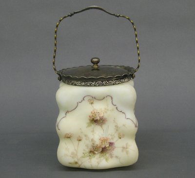 Wavecrest cracker jar: A turn of the century Wavecrest cracker jar. Molded glass body with enameled floral decoration and Silver plated handle and cover. Minor surface wear. 6 1/2" high. ESTIMATE $200-400
