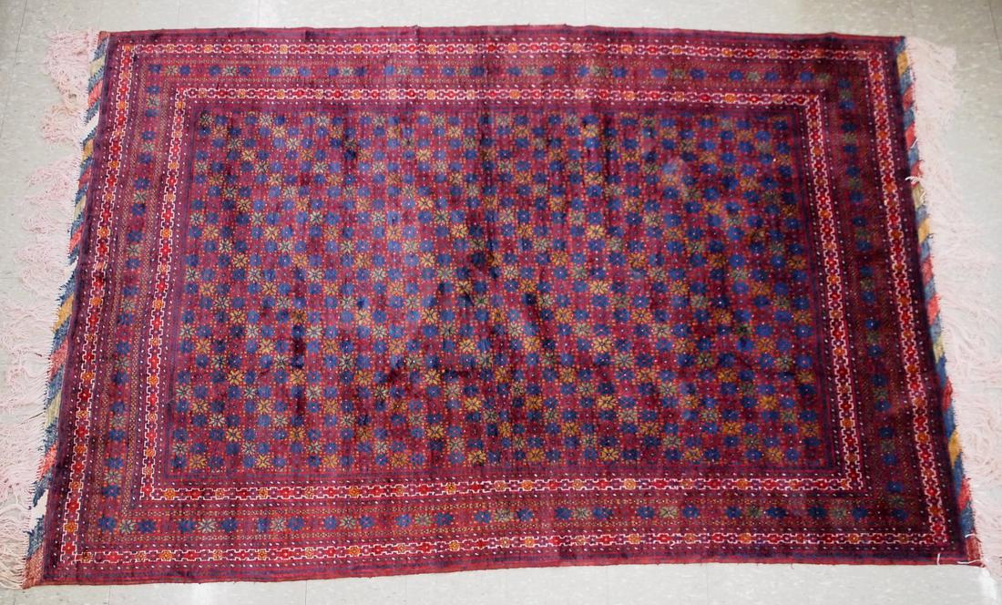 Afghan Rug: A 6.2 x 9.9' Afghan rug. Multi-color floral design on a burgundy field with multiple geometric borders. Wear, some edge damage. ESTIMATE $200-400