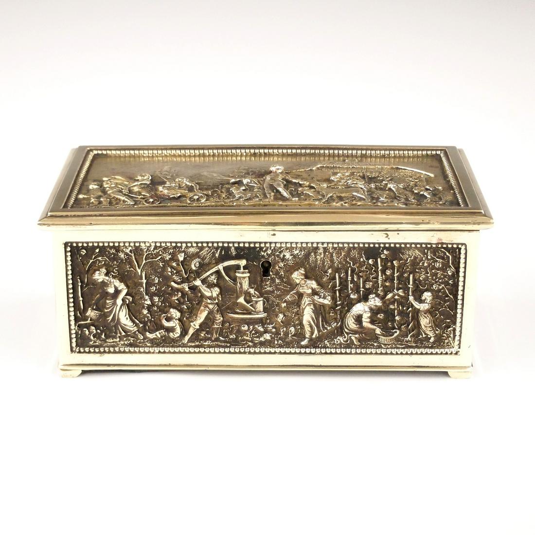 Jewel Casket: An early 20th century Brass jewel casket. Cast panels with landscape design and figures. Includes a village scene and grape harvest. Marked on the bottom with "T". Polished, some wear to lined interio