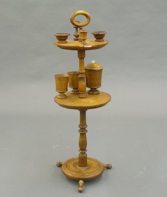Smoking stand: A turn of the century Maple smoker's stand. Two tier design with ring handle, fitted with various caddies and holders, match striker etc., with turned columns and feet. Old finish with wear and minor