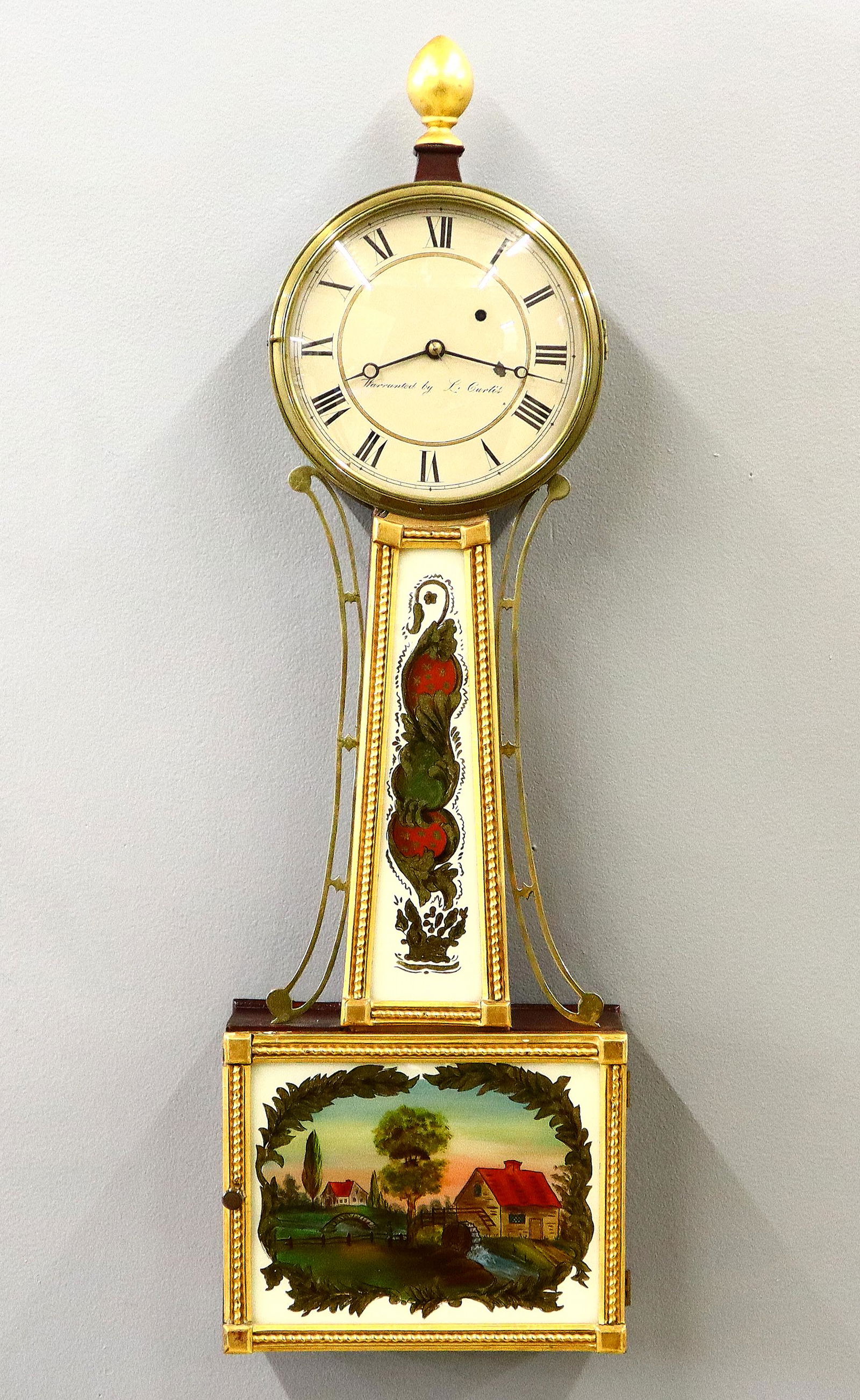 L Curtis Banjo Clock: A mid 19th century American banjo clock. 8-day time only movement with painted iron dial and Roman numerals signed "Warranted by L. Curtis". Mahogany case with gilded front, turned gilded finial over