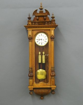 Vienna Regulator wall clock: A late 19th century 2-weight Vienna Regulator wall clock. Walnut case with single long door flanked by carved, fluted columns and carved drop with three turned finials. 8-day time and strike movement