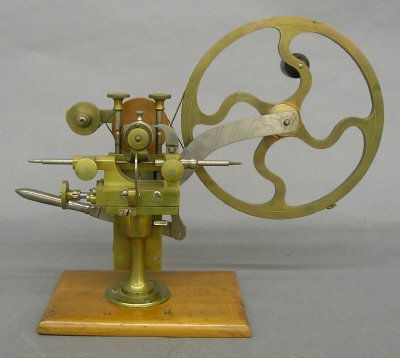 Rounding up tool: A turn of the century Brass and Steel rounding up tool, for cutting small clock and watch gears. Hand crank power with vertical adjustment lever and sliding table, on a molded Mahogany base. Some wear