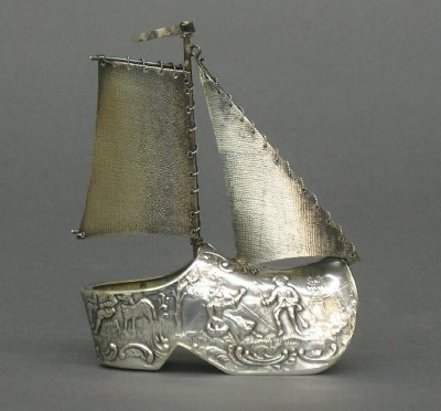 Dutch Silver Ship: An early 20th century Dutch .830 Silver Ship novelty. Shoe form hull with Repousee landscape, engraved sails and "Roped" rigging. Hallmarked. Minor wear. 3 1/4" high. 1.0 troy oz. ESTIMATE $50-100