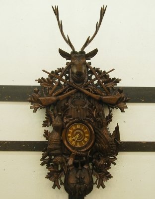 Cuckoo clock: A mid 20th century German Black Forest cuckoo clock. Extensive hand carved design with a large deer head at the top, rifles, game, a hunting horn with Oak leaf detail. Three train weight driven 30 hou
