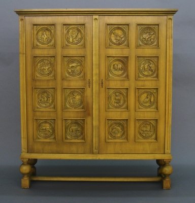 Carved Gun cabinet: A 1950's period carved Birch Gun collector's cabinet. Two hinged doors with carved game panels, interior storage and a turned leg stretcher base. Old finish with wear and minor damage. 56 x 17 x 64" h