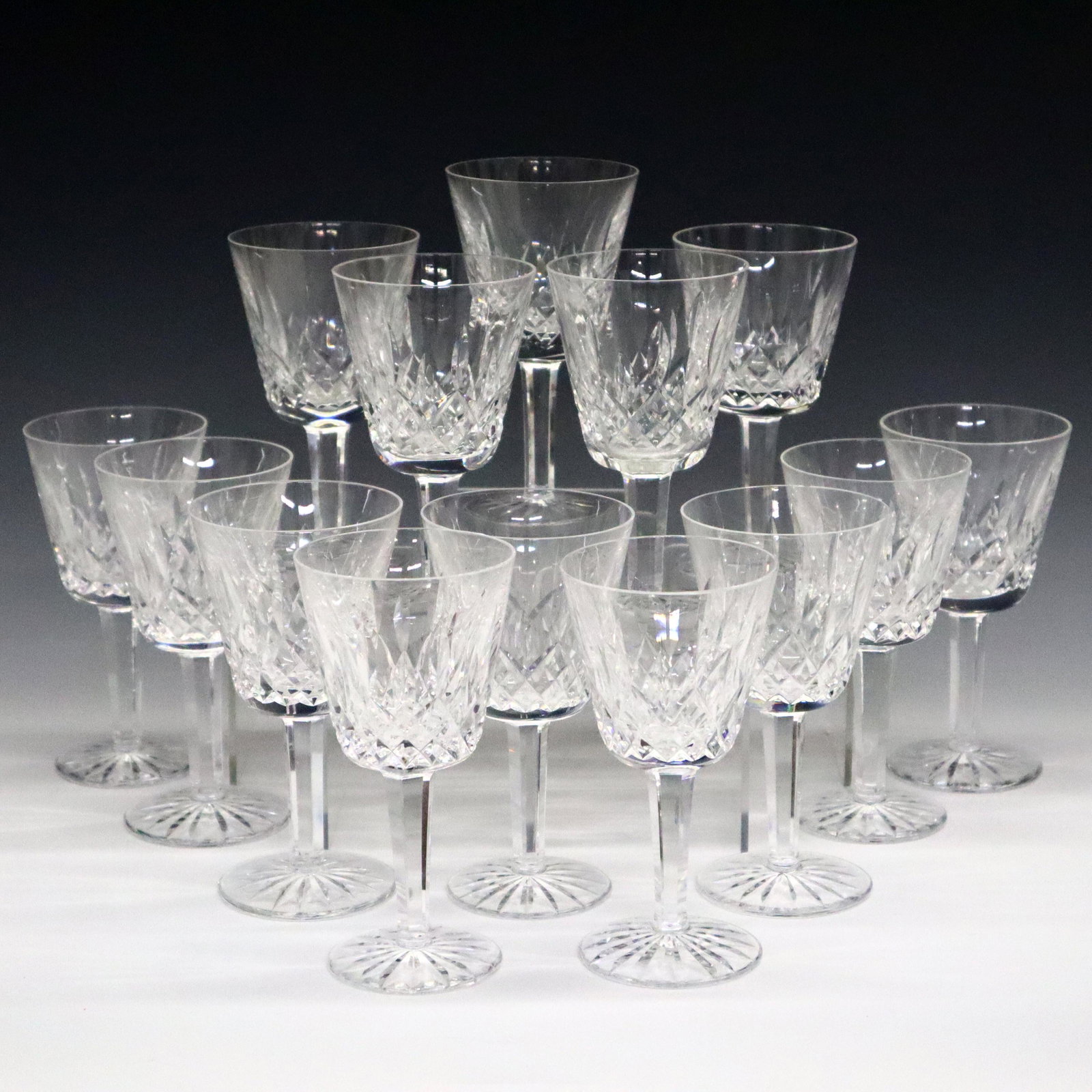 14 Waterford Lismore Wine Glasses: Fourteen late 20th century Waterford "Lismore" pattern Crystal white wine glasses. Very minor wear to bottoms of feet, slight chip to one rim. 5 3/4" high. ESTIMATE $100-200
