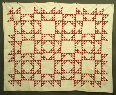 Patchwork quilt: An early 20th century American patchwork quilt. Geometric design in Red and White with Pinwheel quilting. Wear, minor damage and some staining. 69 x 86" overall. ESTIMATE $200-400