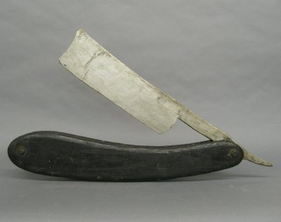 Carved Barbershop sign: A large early 20th century Barbershop sign of a straight razor. Carved wooden construction with Black/Silver painted finish. Some wear and minor damage. 28" long. ESTIMATE $200-300