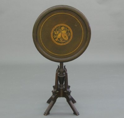 Victorian stand: A late 19th century American Aesthetic period Walnut stand. Circular flip top with inlaid design on a turned stem with four shaped legs. Older finish with wear, some veneer loss and damage. 29 1/2" hi