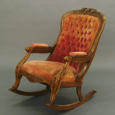 Victorian rocker: A 19th century American Victorian period Walnut rocking chair. Shaped, carved crest with an upholstered back and seat, scrolled arms and shaped rockers. Older finish and upholstery with wear. 41" high