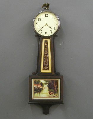 New Haven Banjo clock: A 1920's New Haven "Waring" model Banjo clock. 8-day spring driven time only movement with 8" painted dial. Mahogany case with metal top door and prints in waist glass and lower door. In good running