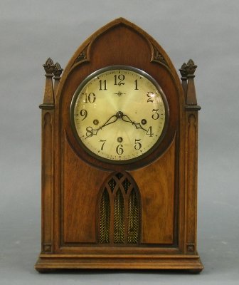 New Haven "Abbey" model Mantle clock: An early 20th century New Haven "Abbey" model Mantle clock. Three train 8 day spring driven time and strike movement with Westminster chimes and Silvered dial. Walnut case with arched top and Gothic s