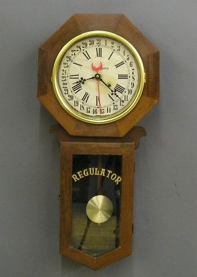 Schoolhouse clock: A 20th century Craftsman made Schoolhouse clock. 31 day spring driven time only movement with simple calendar. Mixed wood long drop case with medium brown finish. Minor wear. 31 1/2" high. ESTIMATE $5