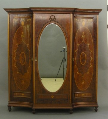 Inlaid Edwardian wardrobe: An exceptional late 19th century English Edwardian period Gentleman's wardrobe. Mahogany with inlaid design including Bell flowers, scroll and patera in Boxwood, Cherry and various Mahoganies. Shaped,