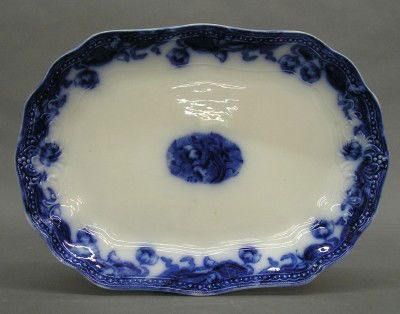 Flow Blue platter: A turn of the century Flow Blue platter. "Geneva" pattern by the New Warf Pottery. Printed mark. Some wear, 1" hairline at rim. 14 1/4" long. ESTIMATE $50-75
