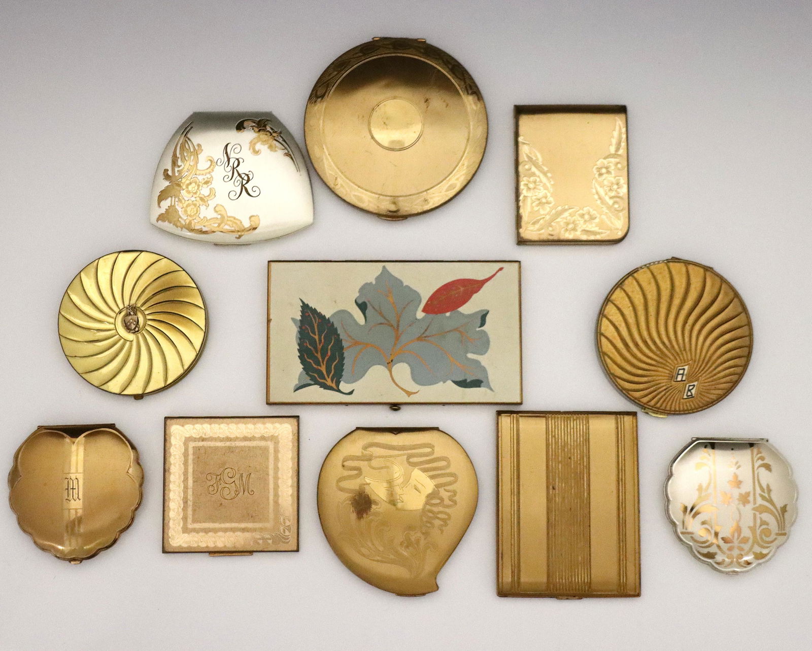 Vintage Compacts & Cigarette Cases: A group of vintage cosmetic compacts and cigarette cases. Etched and molded designs, includes nine compacts and two cigarette cases by Elgin American and Wadsworth. Several with surface wear and monog