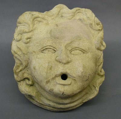 Carved Stone Fountain head: A 20th century carved Limestone Fountain head. Three dimensional mask design of a young child with flowing hair. Wear and minor damage. 12 1/2" high. ESTIMATE $200-300