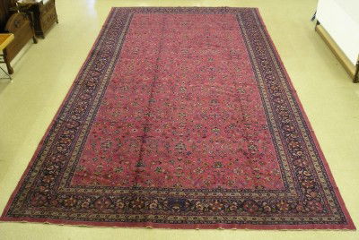 Large Turkish rug: A mid 20th century Turkish hand woven rug. Multi color floral sprays on a Burgundy field with a wide multi pattern border. Wear, some edge damage and rebinding. 12.0 x 23.3' overall ESTIMATE $1,000-2,