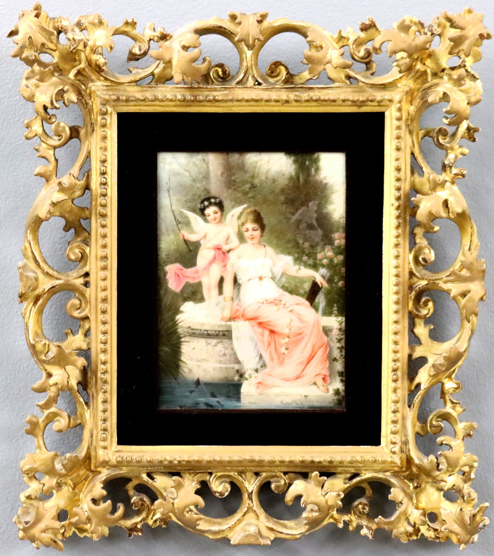 German Porcelain Plaque: A turn of the century German porcelain plaque. Hand-painted depiction of Cupid and Venus fishing from a fountain in Cupid's rose garden. Impressed numerals verso. Minor wear. Image 5 1/4 x 7 1/2" high