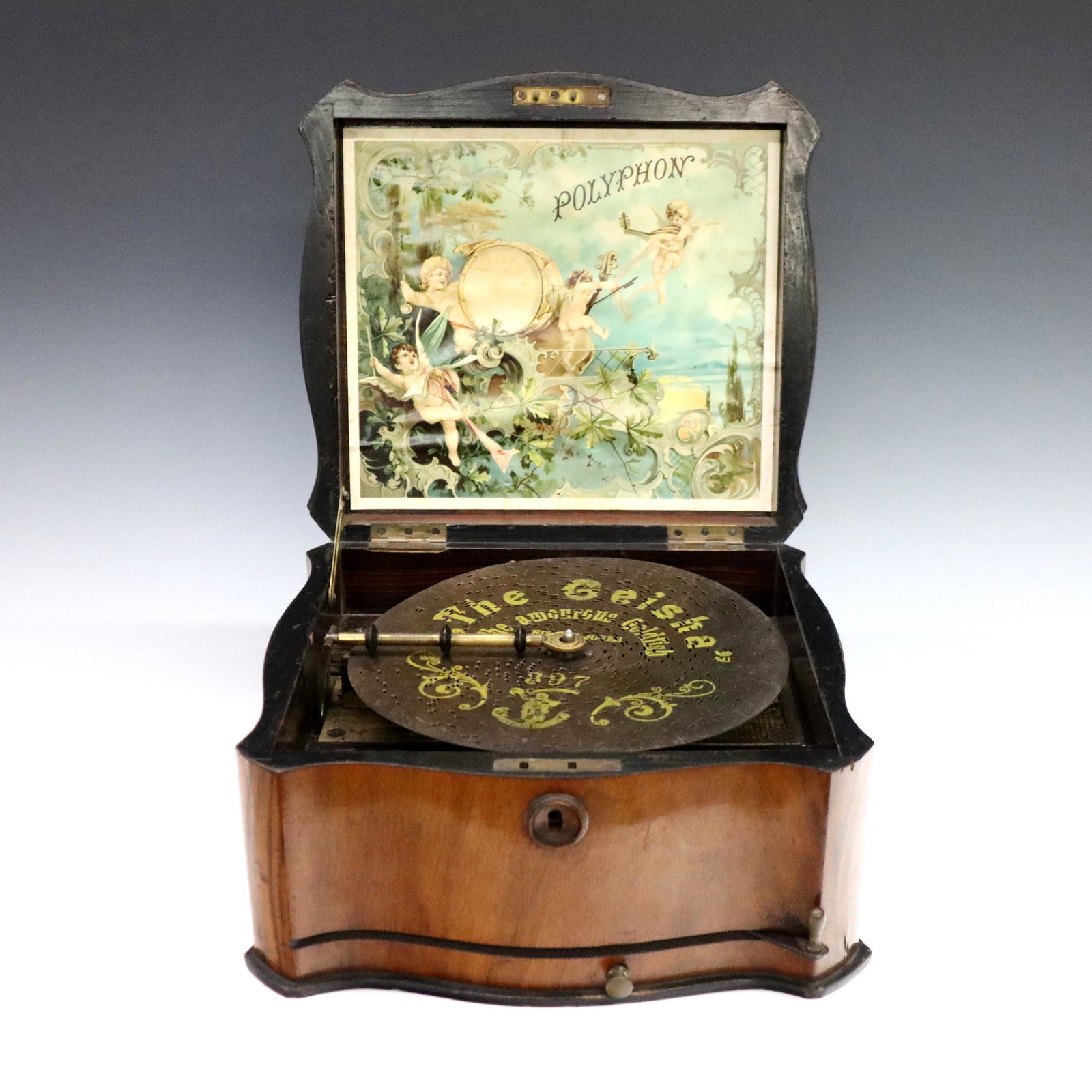 Polyphon Music Box: A turn of the century Polyphon music box with four discs. Single comb crank wind movement serial #122357, plays 8 1/8" discs. Figured Walnut case having a shaped lift top with Ivorene inlay and a mold