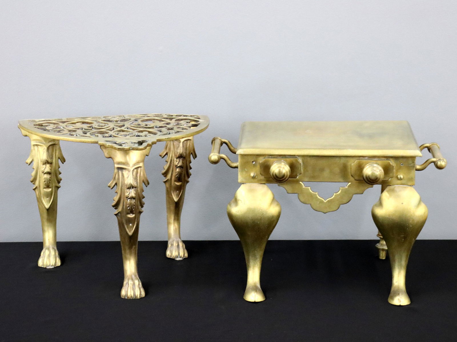 2 Brass Trivets: Two turn of the century British Brass trivets. Includes one with solid molded top and side handles on cabriole front legs, the other with pierced top on three cabriole legs and lion paw feet. Surface