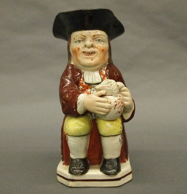 Early Toby jug: An early 19th century Staffordshire Toby jug with original polychrome painted finish. Classic seated figure with an Ale jug on his knee. Some wear, old repairs to hat and toe of one shoe. 9" high. EST