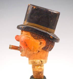 German Musical Bottle Stopper: A 20th century German clockwork musical bottle stopper with a man with top hat smoking a cigar. Spring driven movement plays when placed, hat down, on a table. Hand carved wooden construction with