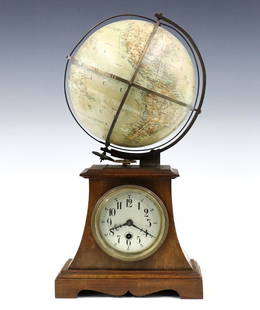 French Globe Clock: A turn of the century French desk clock with globe. 30-hour time only German movement with balance wheel escapement, Silvered dial and Arabic numerals, also drives the 7" upper terrestrial globe with