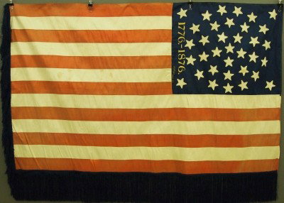 A. Whipple Centennial flag: A 19th century Centennial flag by "A. Whipple, Albany, N. Y.". Sewn Silk construction with "1776--1876" embroidered in Gold, and Navy Blue fringe on two sides. Some wear, staining and overall fading, 