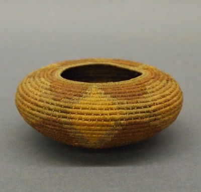 Southwest coiled basket: An early 20th century Native American coiled basket. Very fine work with dyed geometric design. Probably Arizona origin. Minor wear. 5" diameter. ESTIMATE $200-300