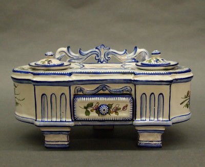 Faience inkstand: A late 19th century French Faience inkstand. Earthenware body with scrolled back, double inkwells and lower drawer. Minor edge damage. 9 1/2" long. ESTIMATE $200-300