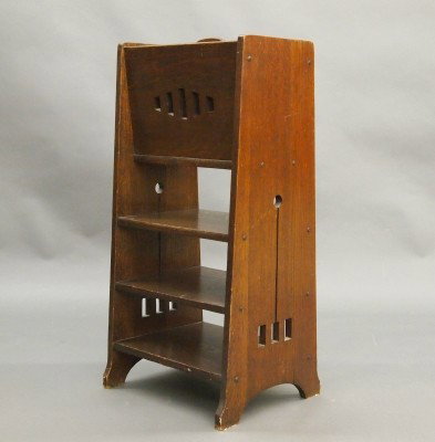 Arts & Crafts library stand: An American turn of the century Arts & Crafts period Oak library stand. Compartmented upper section with cut out detail above a shelved lower section with cut out tapering ends. Original dark finish w