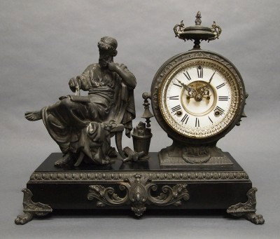 Ansonia Figural clock: A late 19th century Ansonia "Philosopher" model figural clock. 8-day time & strike movement with open escapement and 2 part porcelain dial. Enameled Iron case with "Silvered" Spelter fittings. Minor c