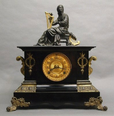 Ansonia mantle clock: A turn of the century Ansonia "Cambridge" model Iron mantle clock with patinated Spelter figure. 8-day time and strike movement. Minor wear. 18 1/2" high overall. ESTIMATE $200-300