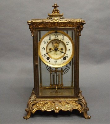 Ansonia Crystal Regulator: A turn of the century Ansonia Bronze table clock. 8-day spring driven time and strike movement with 2-part porcelain dial. Cast Bronze case with foliage design and Patinated finish. Some wear to case,