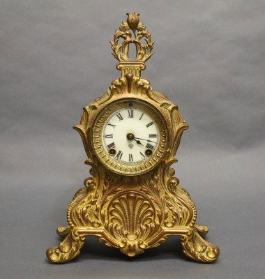 Ansonia Bronze clock: A turn of the century Ansonia Bronze table clock. 8-day spring driven time and strike movement with porcelain dial. Cast Bronze case with Shell and foliage design and Patinated finish. Some wear, and 