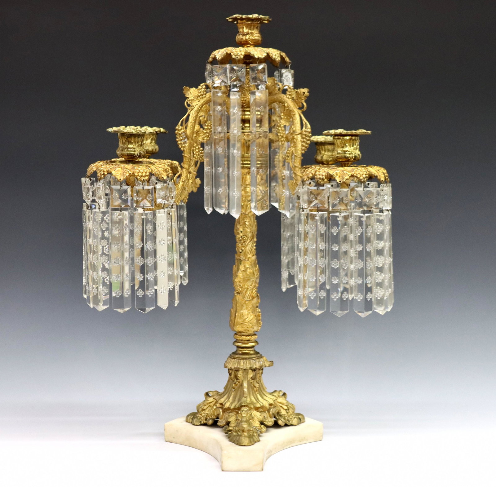 American Bronze Girandole: A mid 19th century American Bronze and Marble girandole. Gilt Bronze construction with grape vine design, four scrolled arms and foliate candle cups with tiered prisms over a baluster stem and tripod 