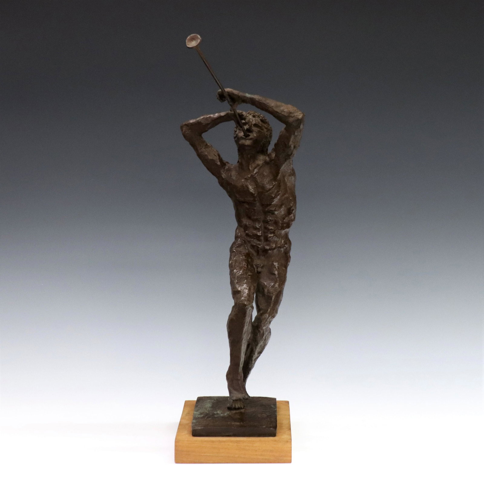 Bronze Musical Figure: A 1960's patinated Bronze musical figure. Depicts a nude man playing the trumpet on a rectangular wooden base. Initialed "RAE", dated "1967" and numbered "1/2" at foot. Minor wear and oxidation to pat
