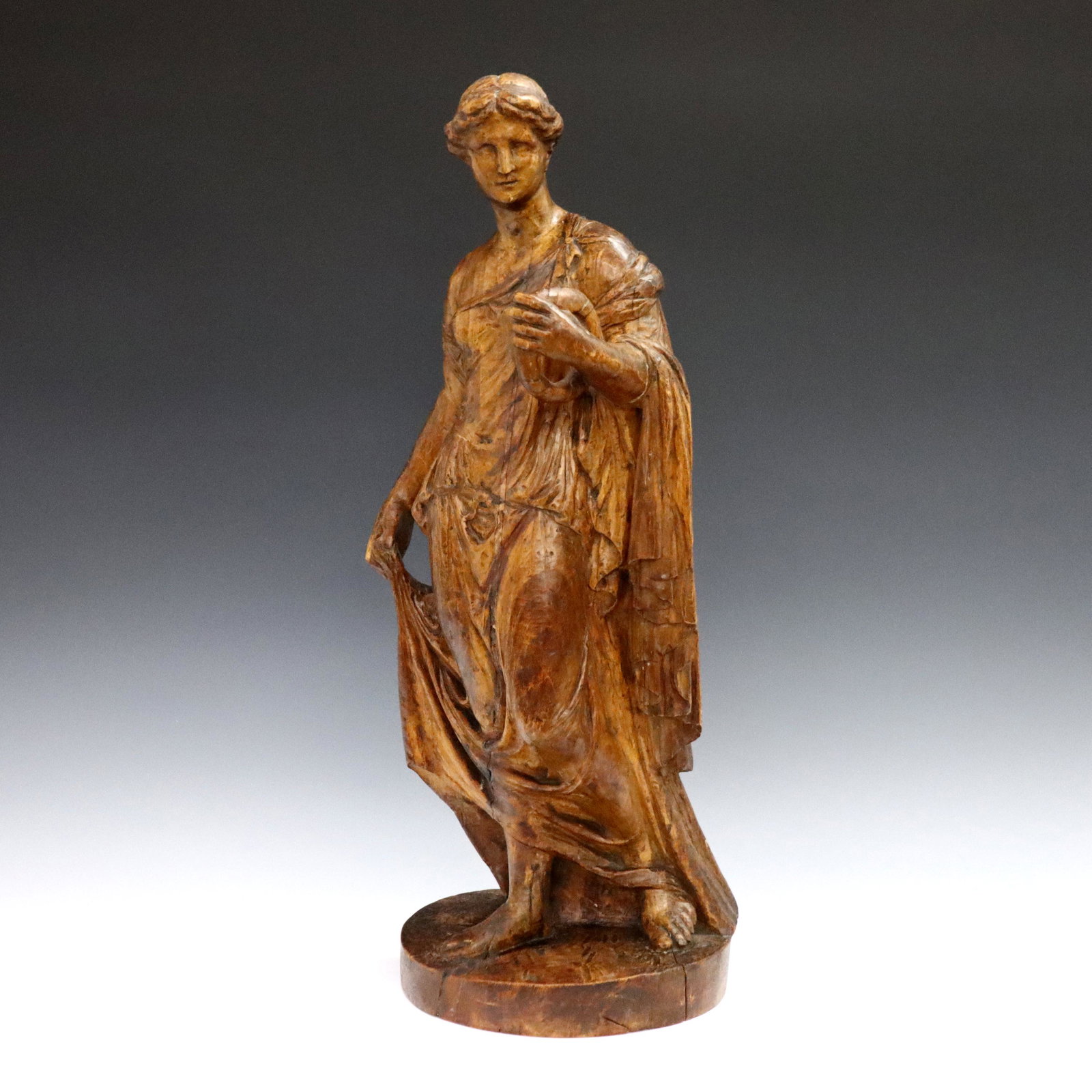 Italian Carved Figure: An 18th century Italian carved hardwood figure. Depicts a Neoclassical goddess holding a wreath with old painted finish. Minor damage, some shrinkage. 19 3/4" high. ESTIMATE $400-600