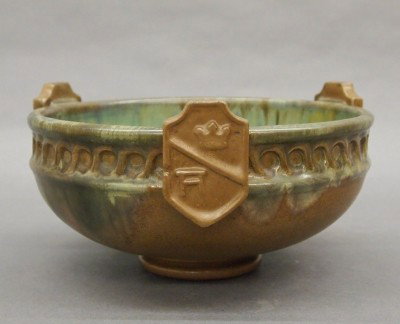 Fulper Pottery bowl: A 20th century Fulper Art Pottery bowl. Low footed form with molded rim and three applied shields in a Tan Matte glaze with Green Flambe. Stamped vertical "Fulper" mark. Minor surface wear, glaze flak