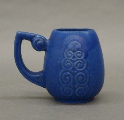 Fulper Pottery mug: A 20th century Fulper Art Pottery mug. Molded Art Deco design with scrolled handle in a Matte Blue glaze. Stamped vertical "Fulper" mark. Minor surface wear. 4" high. ESTIMATE $50-100