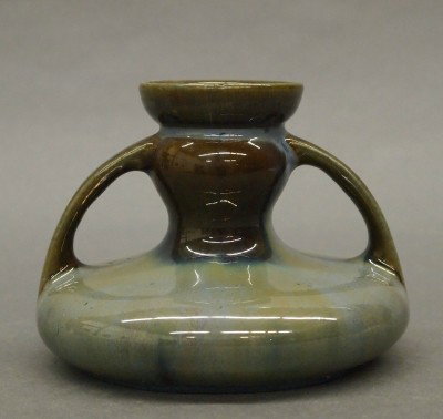 Fulper Pottery candlestick: A 20th century Fulper Art Pottery candlestick. Short two handle design in a Blue/Brown glaze. Stamped vertical "Fulper" mark. Slight surface wear, flake in foot. 3 1/2" high. ESTIMATE $50-75