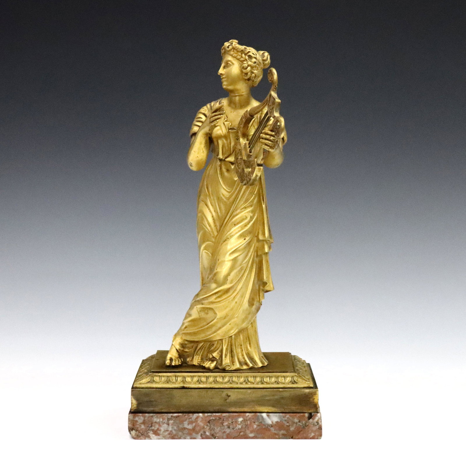 French Bronze Figure of Terpsichore: A late 19th century French Gilded Bronze figure of the Greek muse Terpsichore. Depicted standing with a harp, on a molded base with foliate design and Marble plinth. Minor wear, older glued repair to 