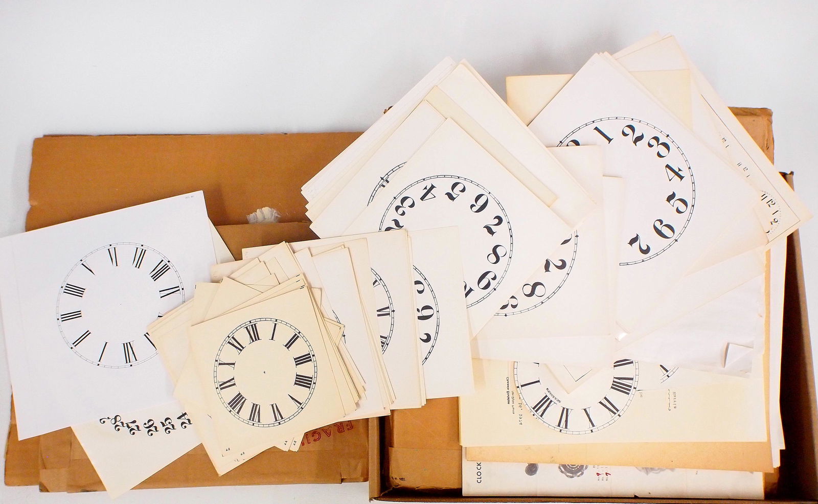 Paper dials: Over 50 paper replacement clock dials. Various sizes from 4" to 12" including some calendar dials. As/Found. ESTIMATE $20-30