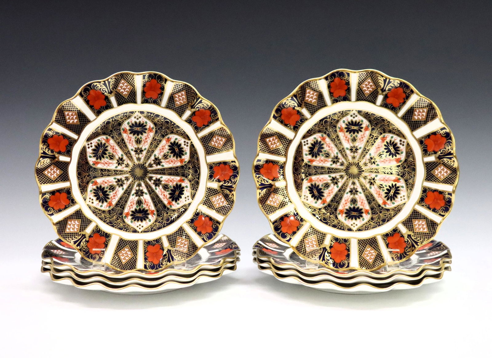 8 Derby Old Imari Dessert Plates: Eight 20th century Royal Crown Derby "Old Imari" pattern fine bone china scalloped dessert plates. Printed marks in Red with "1128" and "LII". Very slight surface wear, one plate with flake at undersi