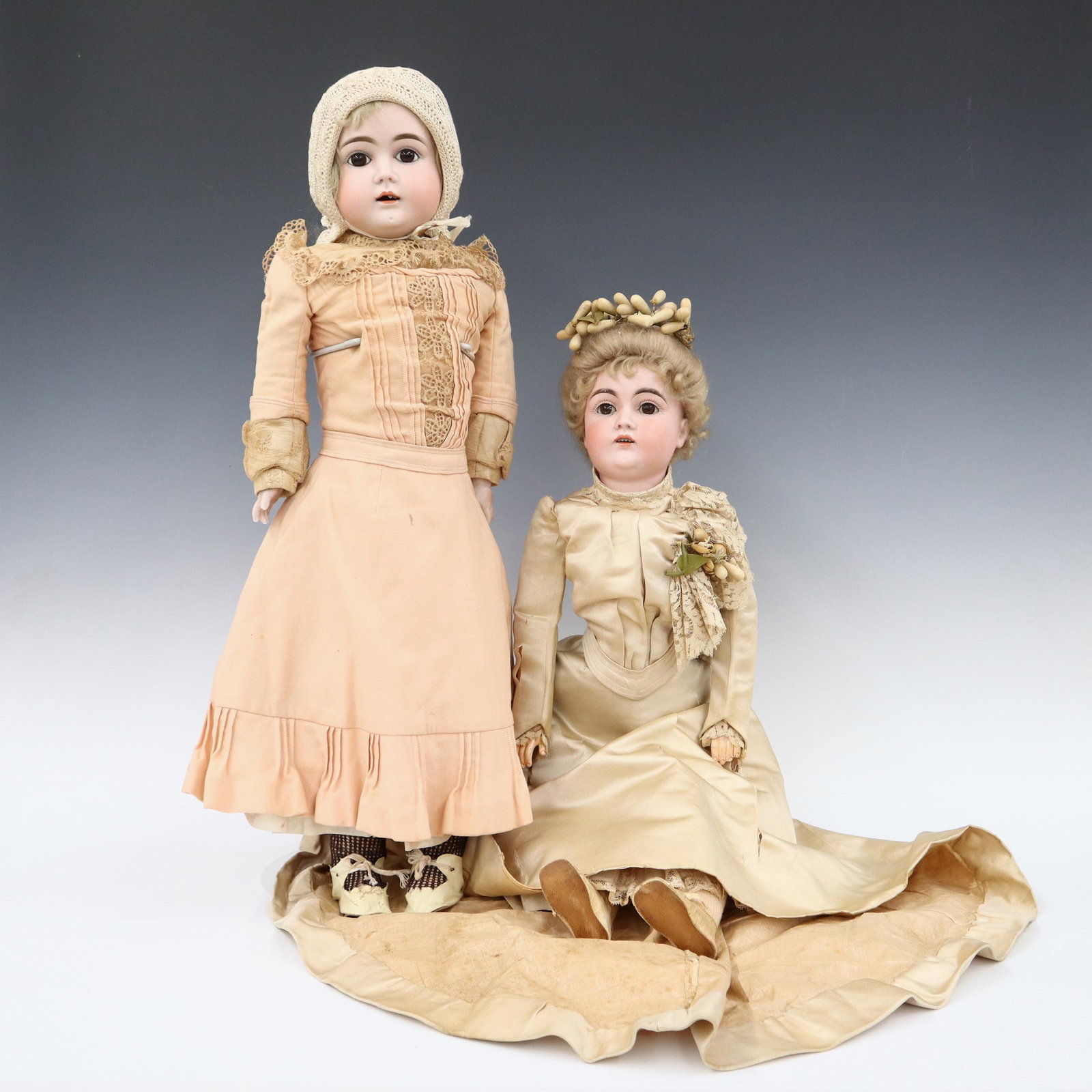 2 German Bisque Dolls: Two turn of the century German dolls. Bisque heads with Blonde hair, open mouths with teeth and painted detail. Includes a full head doll with stationary eyes on a kid jointed body with Bisque lower a