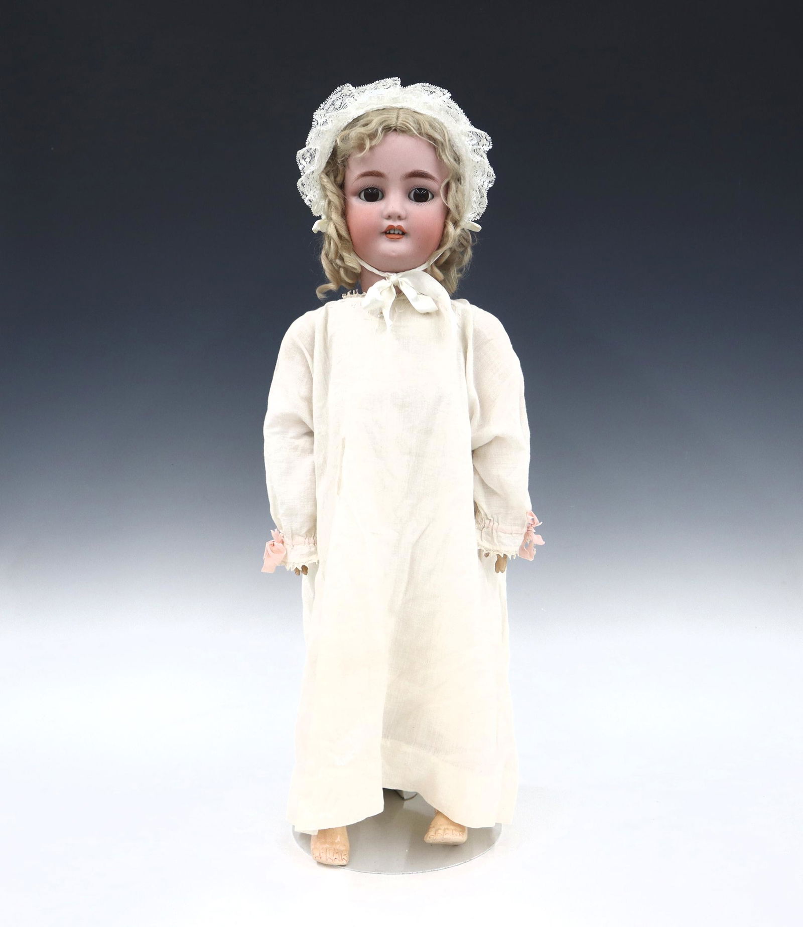 Bergmann, Simon & Halbig Bisque Doll: A late 19th century Bergmann, Simon & Halbig doll. Bisque socket head with Blonde hair, sleep eyes, open mouth with teeth, pierced ears and painted detail. On a jointed composition body, wearing a Whi